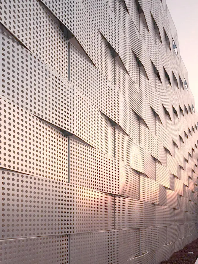 Decorative perforated sheet metal used for building facade, creating unique visual appeal and dynamic light and shadow effects.